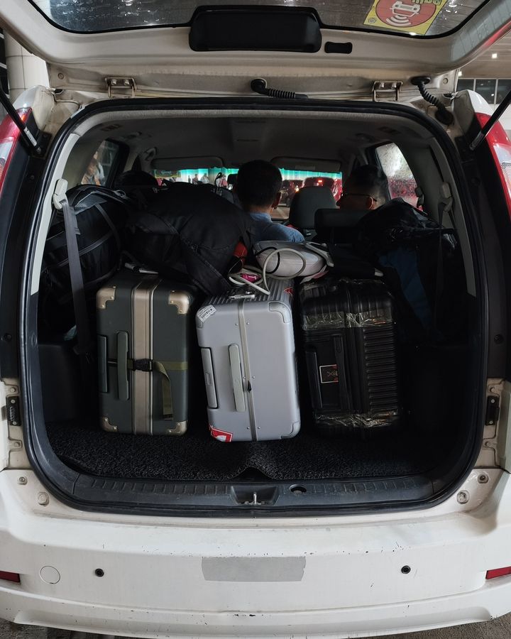 Suitcases packed into the boot of our white Proton Exora on a real trip