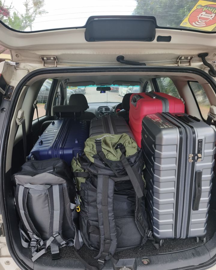 Suitcases packed into the boot of our white Proton Exora on a real trip