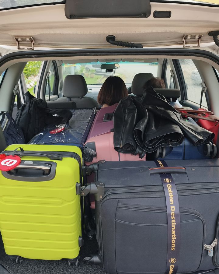 Suitcases packed into the boot of our white Proton Exora on a real trip